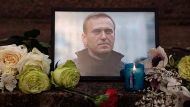 Ein Porträt von Alexej Nawalny, Kerzen und Blumen sind an einer Gedenkstätte niedergelegt.