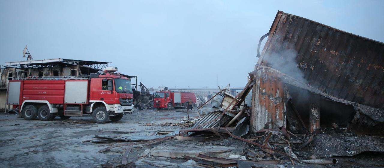 Feuerwehrwagen stehen neben zerstörten Gebäuden.