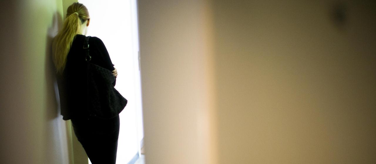 Eine Frau lehnt sich gegen eine Wand.