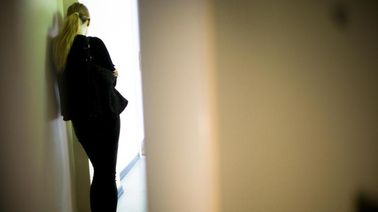 Eine Frau lehnt sich gegen eine Wand.