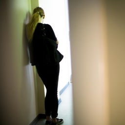 Eine Frau lehnt sich gegen eine Wand.