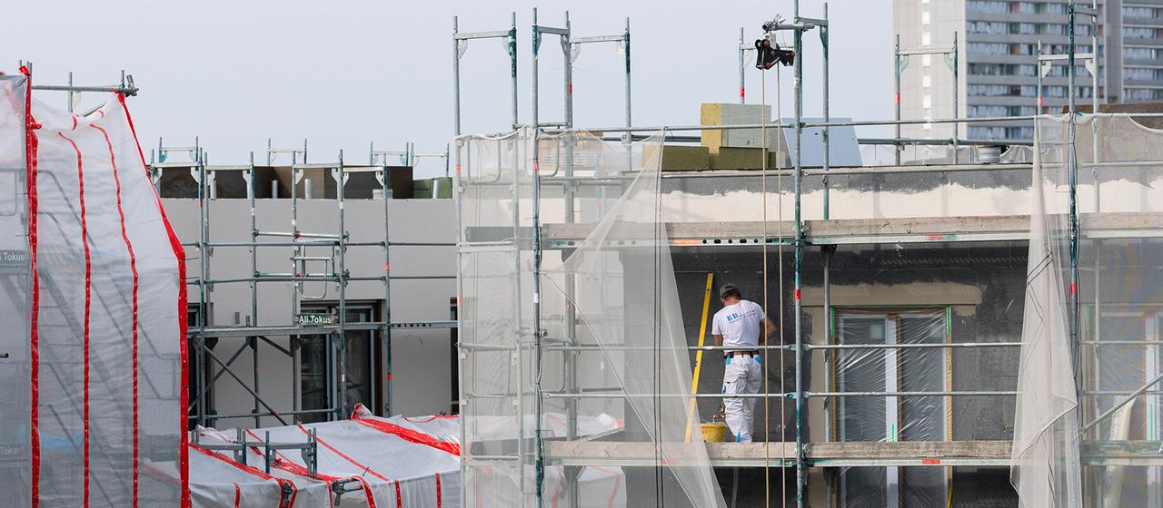 Bauarbeiter verputzen eine gedämmte Fassade auf einer Baustelle in Köln
