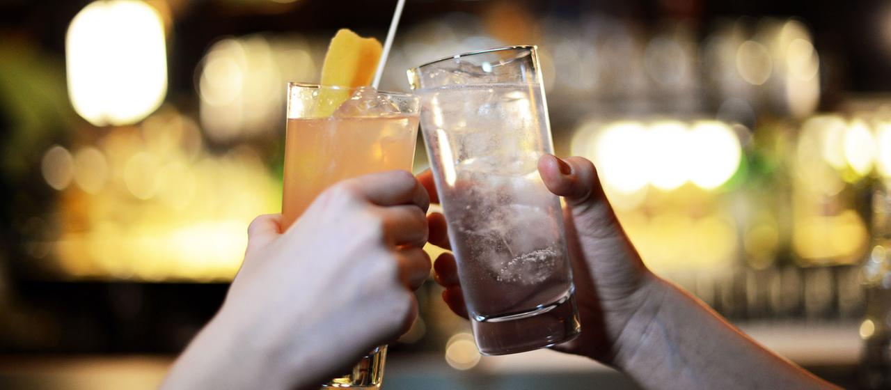 Zwei Menschen stoßen mit Longdrinks an.