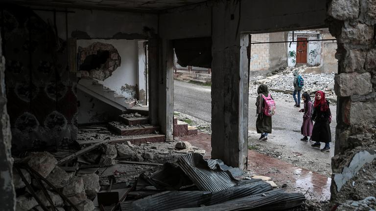 Kinder gehen an einem  zerstörten Gebäude in Idlib vorbei. (Archivbild: 2022)