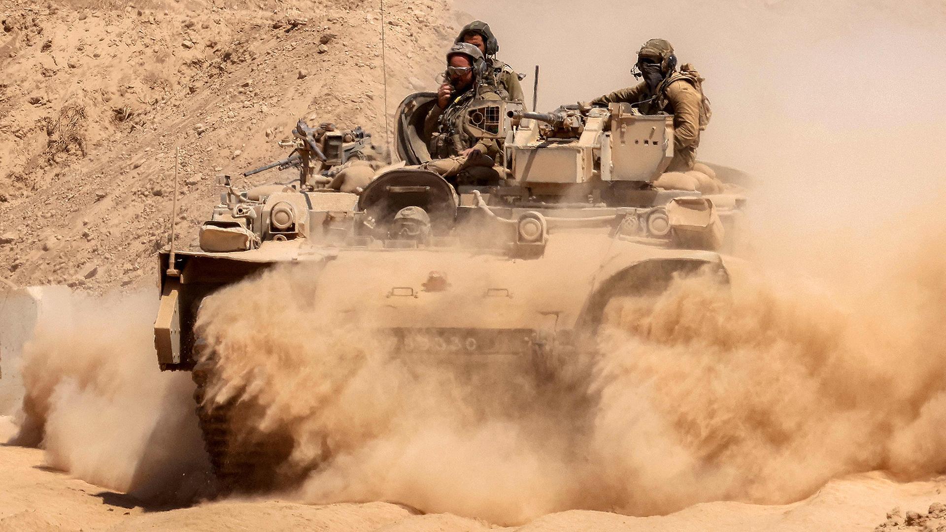 Ein Schützenpanzer der israelischen Armee hinterlässt eine Staubwolke an der Grenze zum Gazastreifen. | AFP