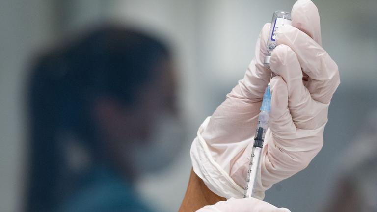 Eine Frau zieht eine Dosis des Impfstoffes von BioNTech/Pfizer für eine Corona-Impfung auf.