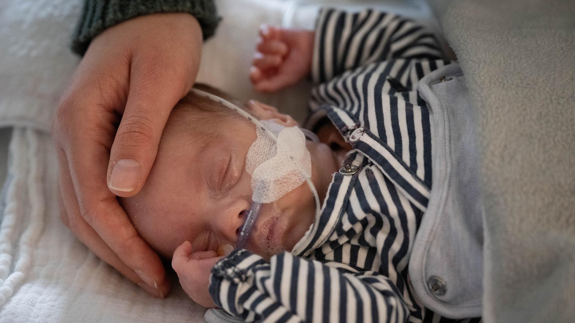 Mit ihrer Hand umfasst die Mutter den Kopf ihres kleinen Sohnes. | picture alliance/dpa