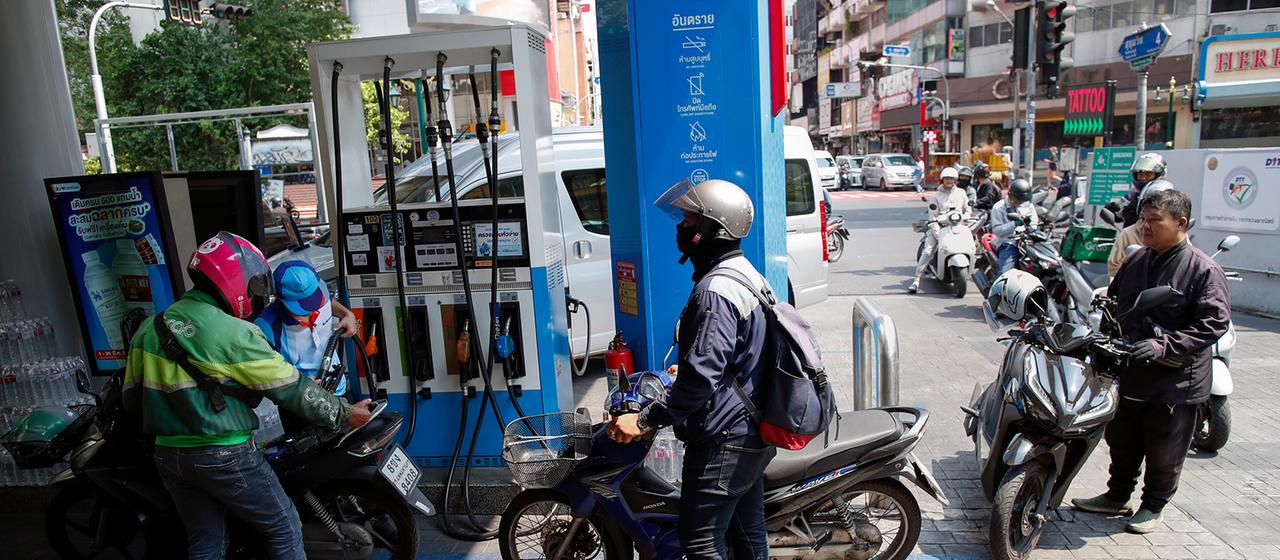 Mopedfahrer stehen an einer Tankstelle im thailändischen Bangkok in der Schlange.