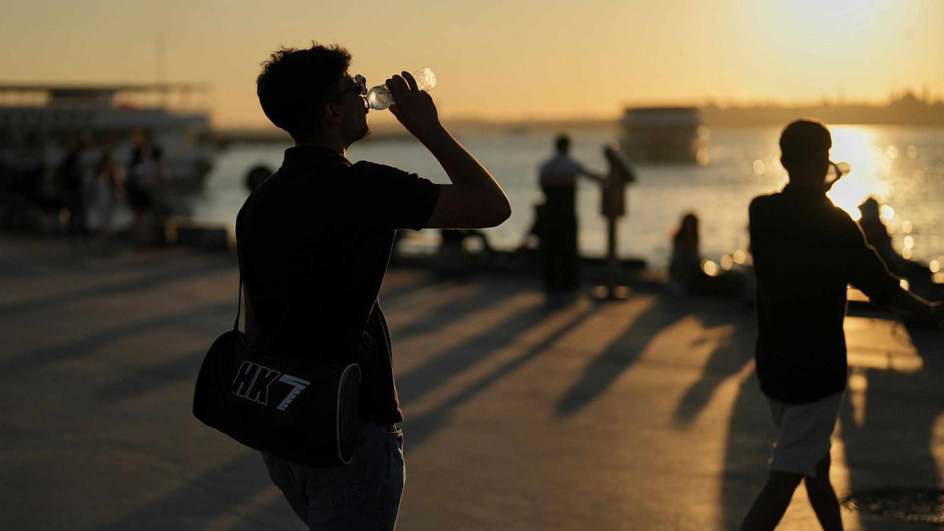 Menschen trinken Wasser an einem heißen Sommertag an der Strandpromenade von Kadikoy in Istanbul, Türkei | AP