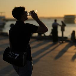Menschen trinken Wasser an einem heißen Sommertag an der Strandpromenade von Kadikoy in Istanbul, Türkei