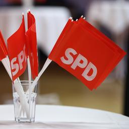 SPD-Fähnchen stehen in einem Glas auf einem Tisch.