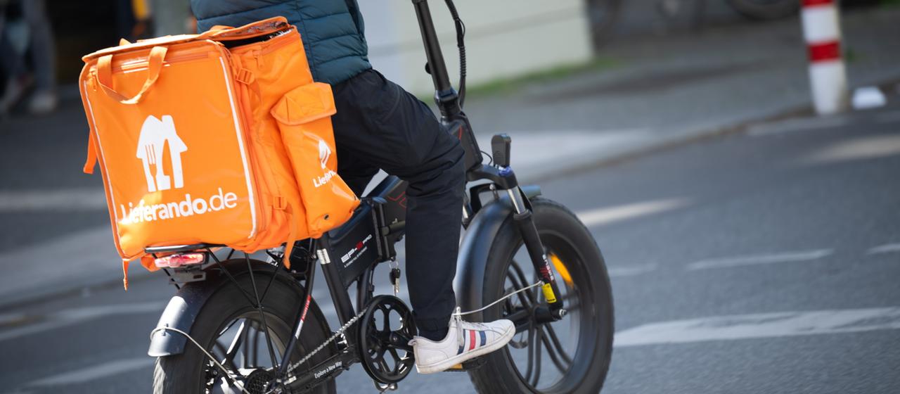 Ein Fahrer für den Essenslieferdienst Lieferando fährt über eine Straße
