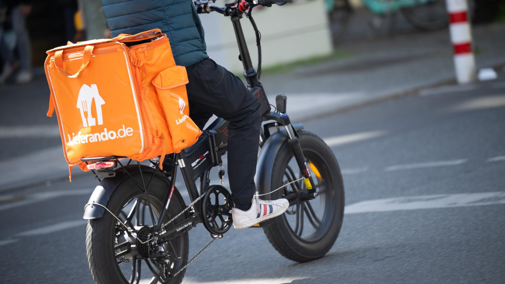 Ein Fahrer für den Essenslieferdienst Lieferando fährt über eine Straße | dpa