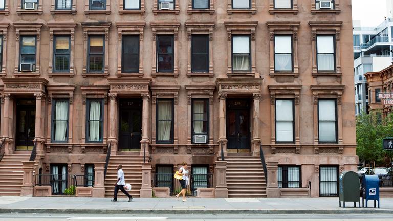 Fußgänger gehen an Wohnhäusern in Harlem (New York, USA) vorbei.