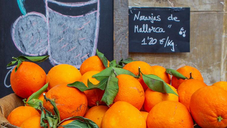 Orangen liegen vor einem Café in der Altstadt von Palma de Mallorca zum Verkauf.
