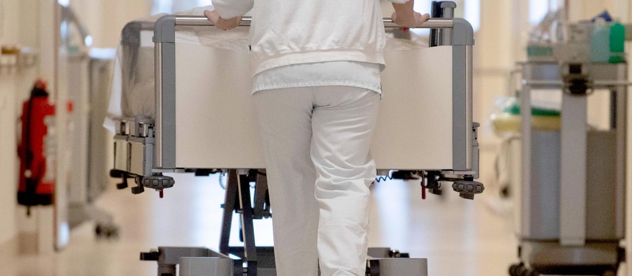 Eine Krankenschwester schiebt ein Krankenhausbett durch einen Krankenhausflur