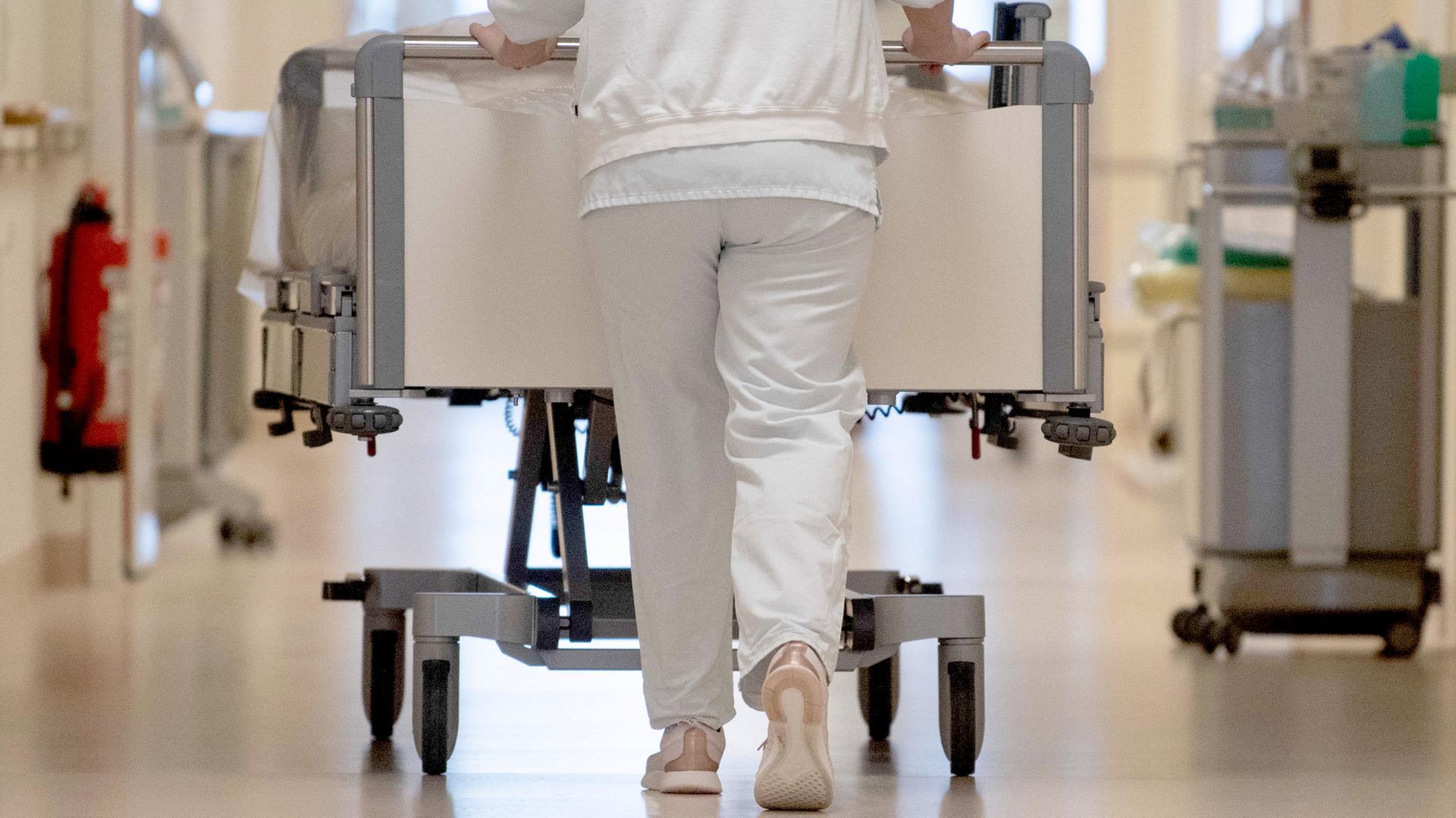 Eine Pflegerin schiebt ein Krankenbett durch einen Klinikflur | dpa