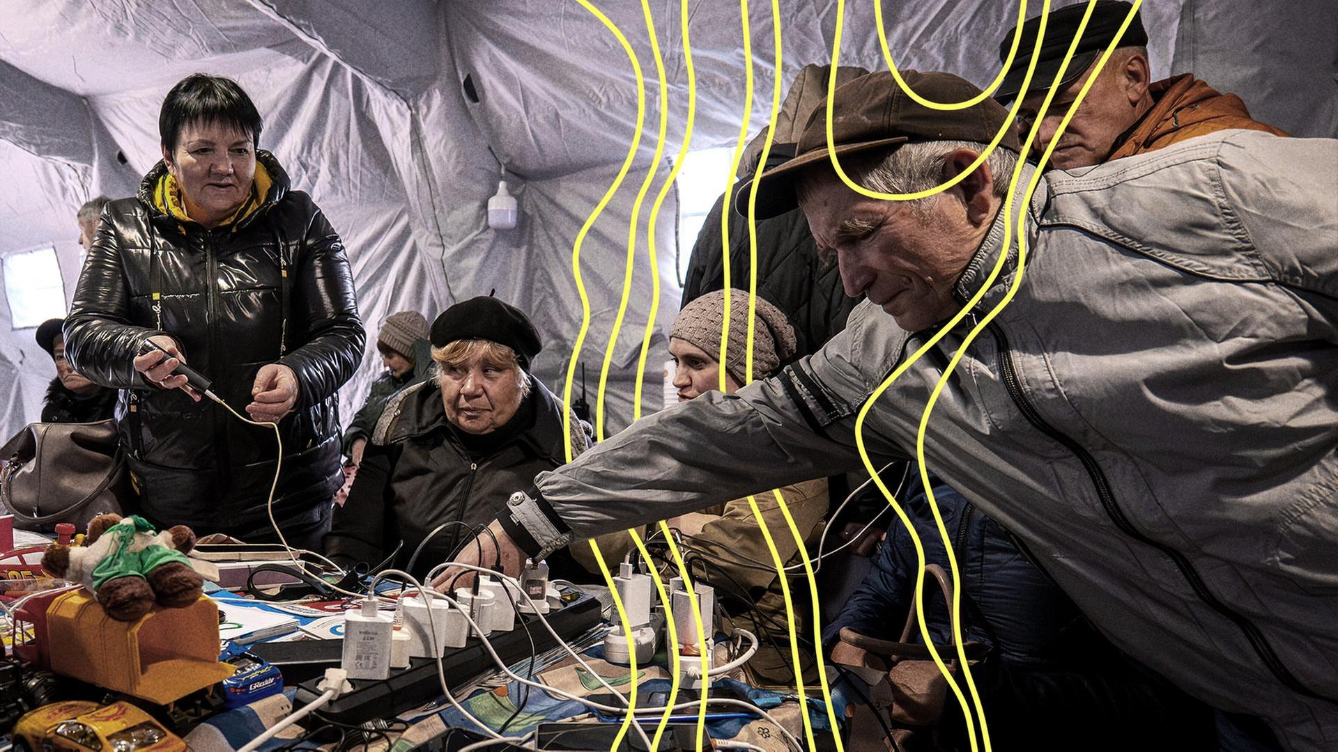 Während eines totalen Stromausfalls nach russischen Luftangriffen auf die Energieversorgung in Tschernihiw, Ukraine, am Dienstag laden Menschen ihre Telefone in einem Zelt auf. | picture alliance/dpa/AP, Dan Bashakov