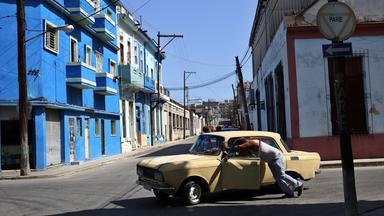 Ein Mann schiebt sein kaputtes Auto durch eine Straße in der kubanischen Hauptstadt