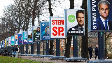 Menschen laufen entlang einer Reihe von Wahlplakaten in Den Haag kurz vor den Parlamentswahlen in den Niederlanden.