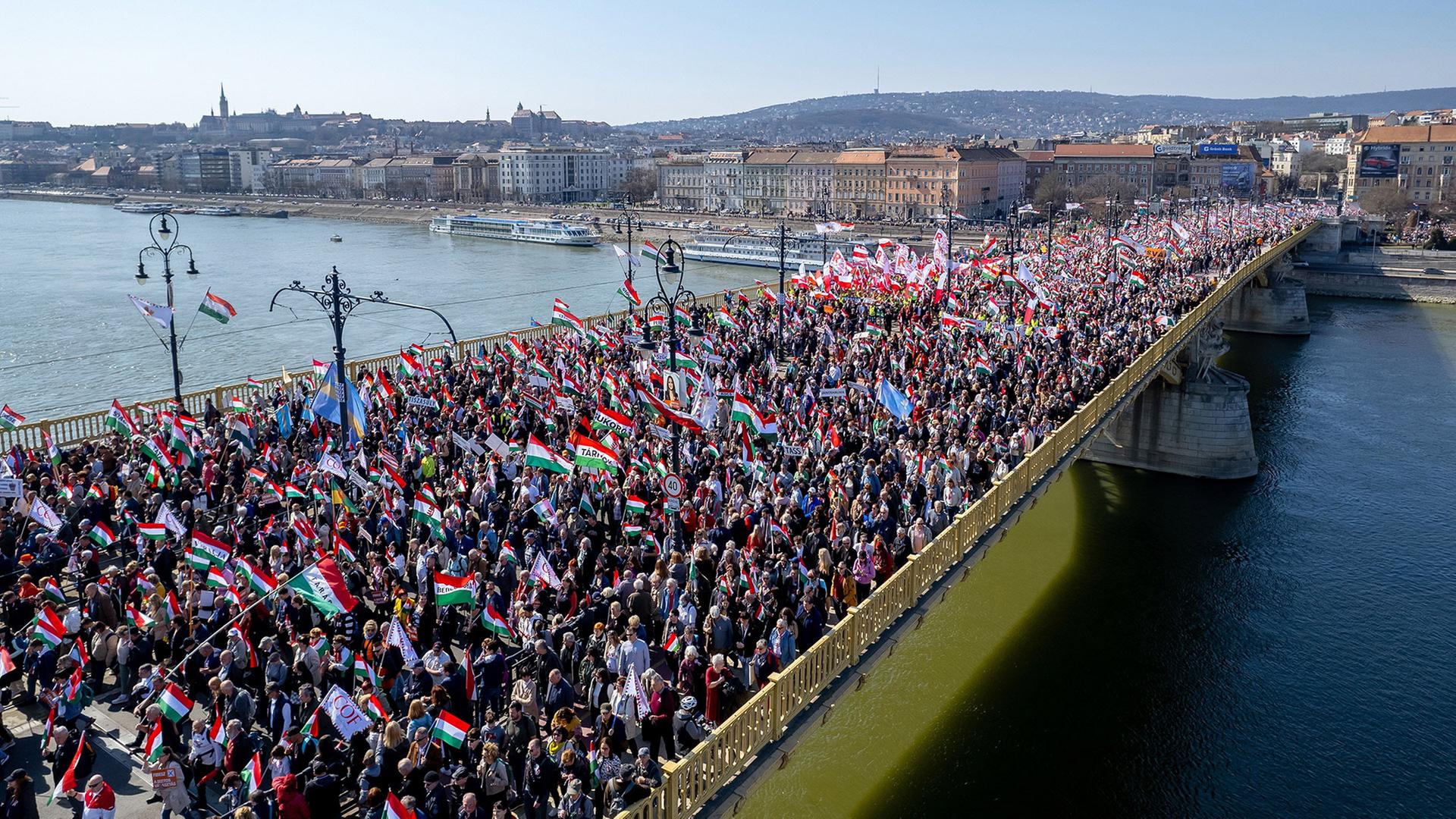 Menschenmassen mit Ungarn-Flaggen laufen auf der Margaretenbrücke in Budapest. | Zsolt Czegledi/MTI/AP/dpa