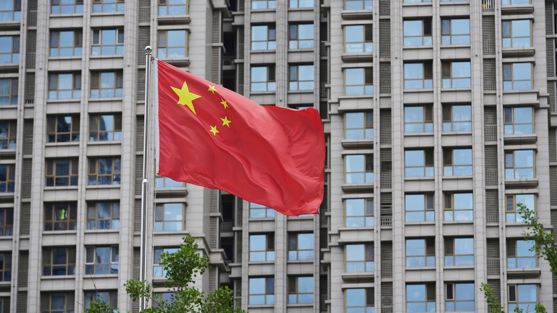 Eine chinesische Fahne weht vor einem Hochhaus. | dpa