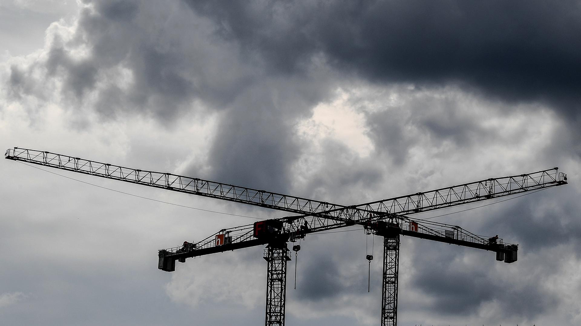 Baukräne sind vor dunklen Wolken zu sehen. | dpa