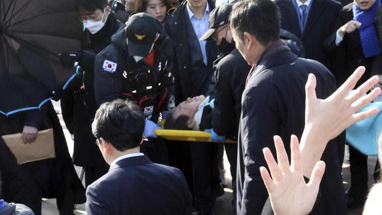 Lee Jae Myung wird nach einer Attacke von Rettungskräften getragen.