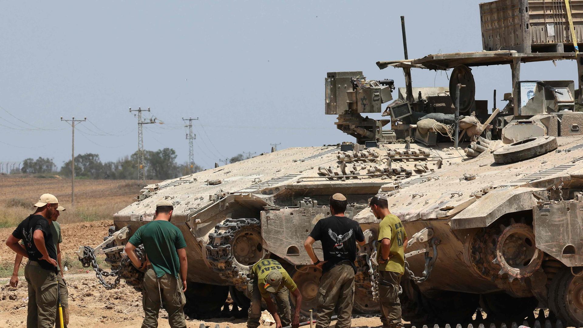 Israelische Soldaten schauen sich an der Grenze zum Gazastreifen eine Pankzerkette . | AFP