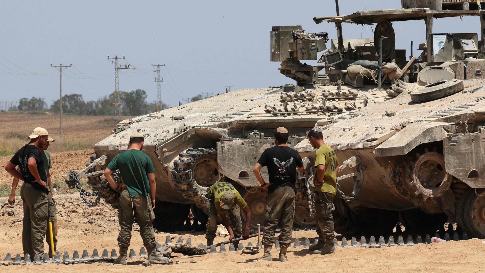 Israelische Soldaten schauen sich an der Grenze zum Gazastreifen eine Pankzerkette an. | AFP