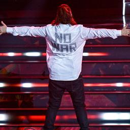 Der italienische Sänger Gianluca Grignani steht mit ausgebreiteten Armen und dem Rücken zum Publikum auf der Bühne bein San Remo Festival 2023, sodass auf seinem Hemd die Aufschrift "No War" ("Kein Krieg") sichtbar ist.