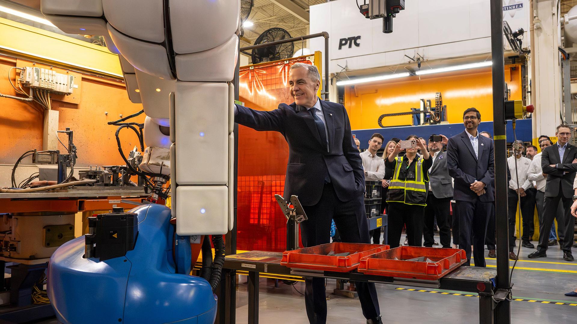 Mark Carney berührt einen Roboterarm in einem Autoteilewerk in Woodbridge. | AP
