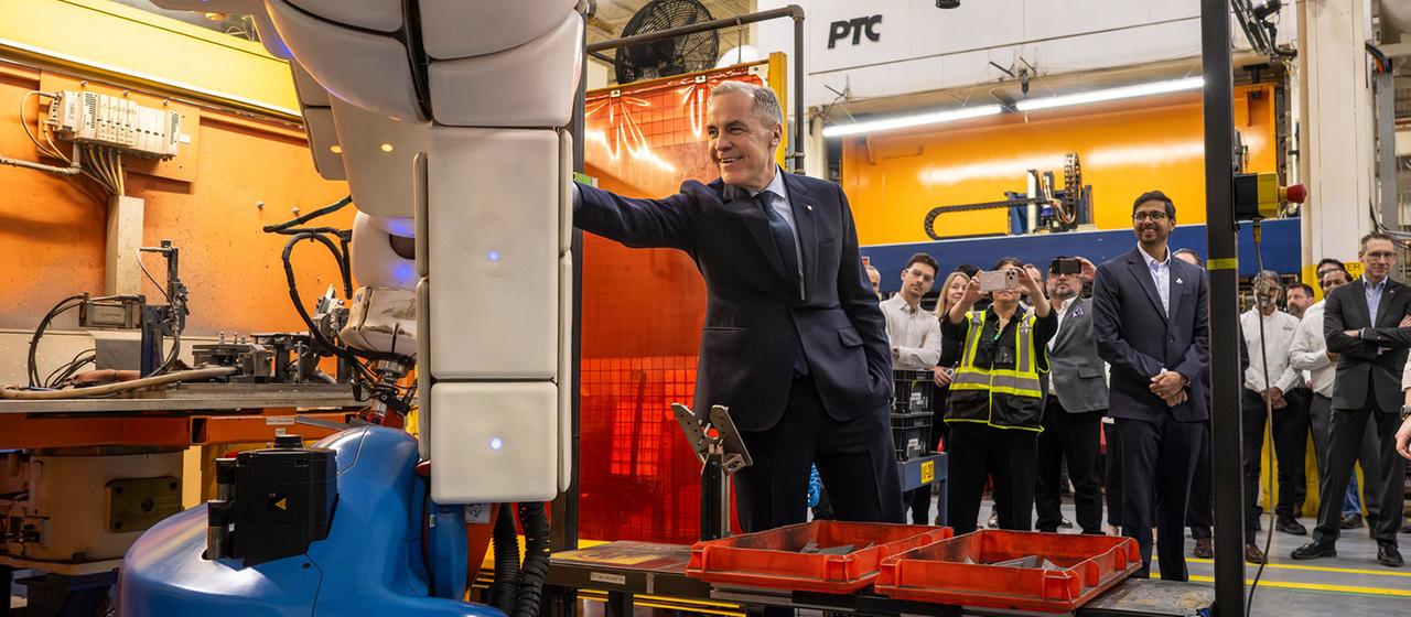 Mark Carney berührt einen Roboterarm in einem Autoteilewerk in Woodbridge.