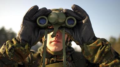 Ein Soldat schaut durch ein Fernglas.