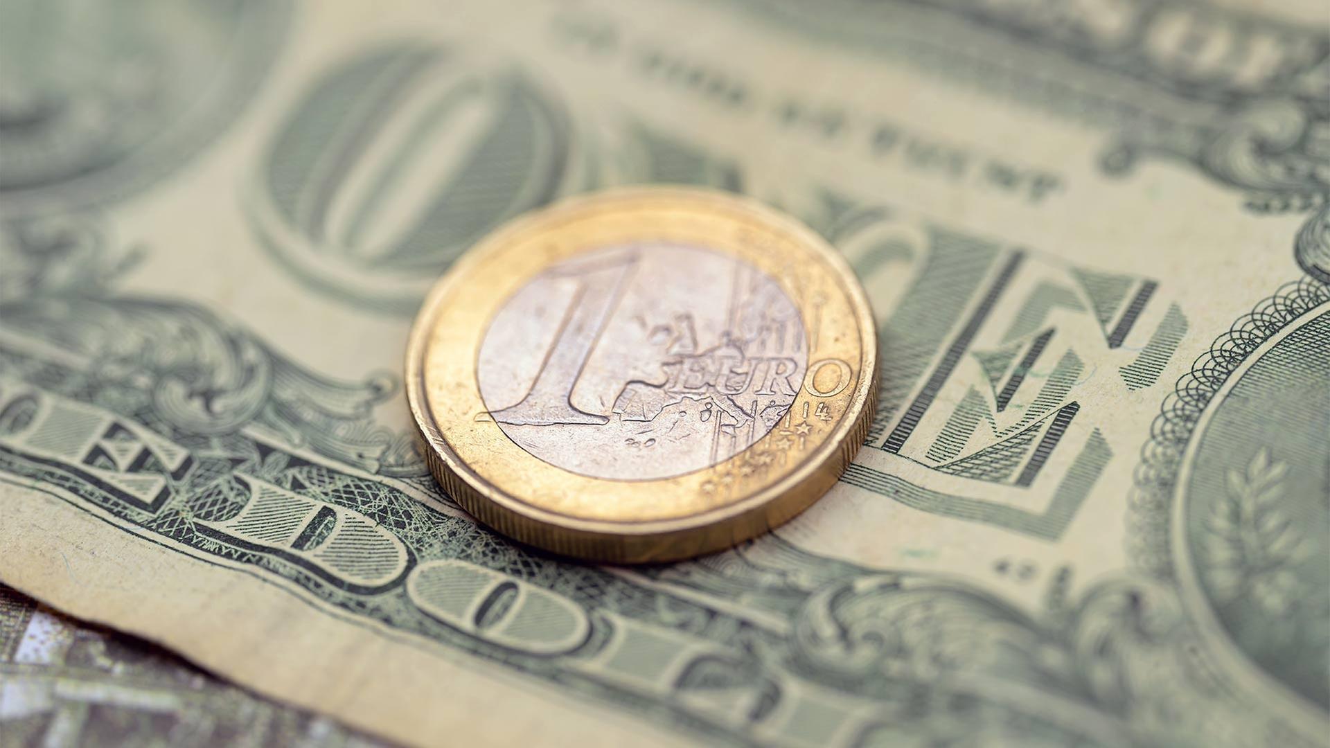 Euromünze auf einem Dollarschein. | picture alliance / NurPhoto