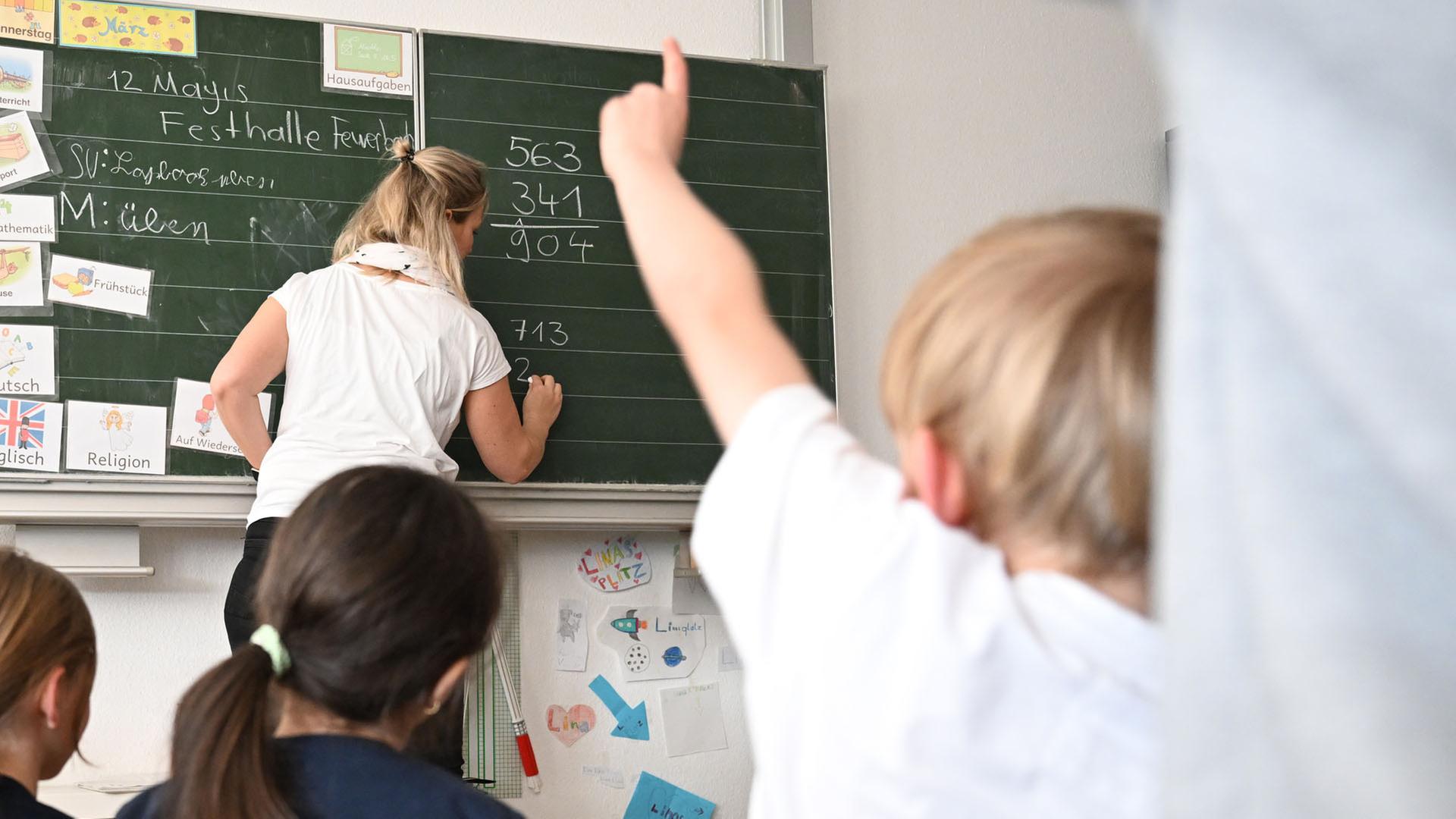 Eine Lehrerin schreibt an einer Tafel. | dpa