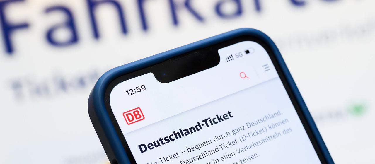 Eine Person hält ein Smartphone in der Hand, auf dessen Display eine Information zum Kauf des Deutschlandtickets zu sehen ist.