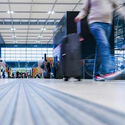 Fluggäste ziehen Rollkoffer durch die Halle von Terminal 1 des Flughafens BER. 