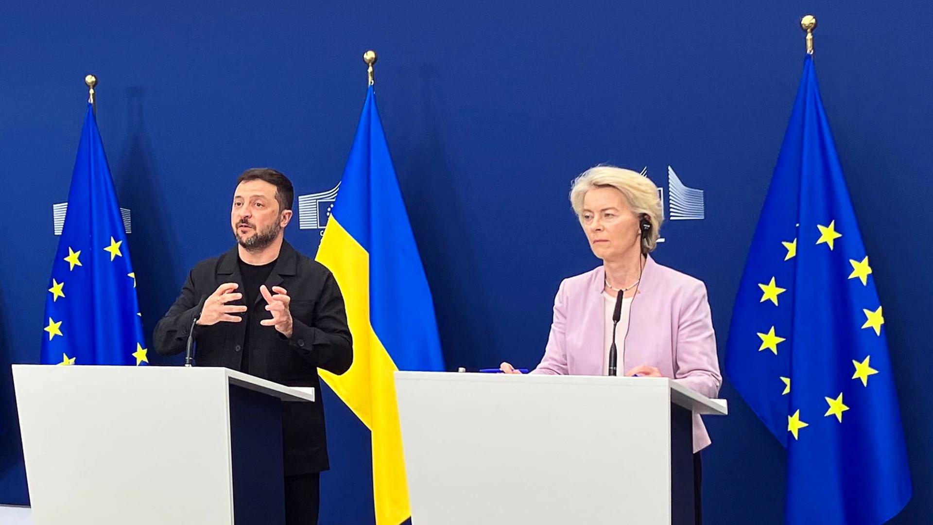 Wolodymyr Selenskyj und Ursula von der Leyen stehen nebeinander an Rednerpulten. | dpa