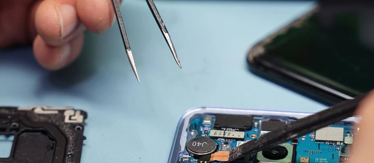An einem geöffneten Smartphone wird eine Reparatur vorgenommen.
