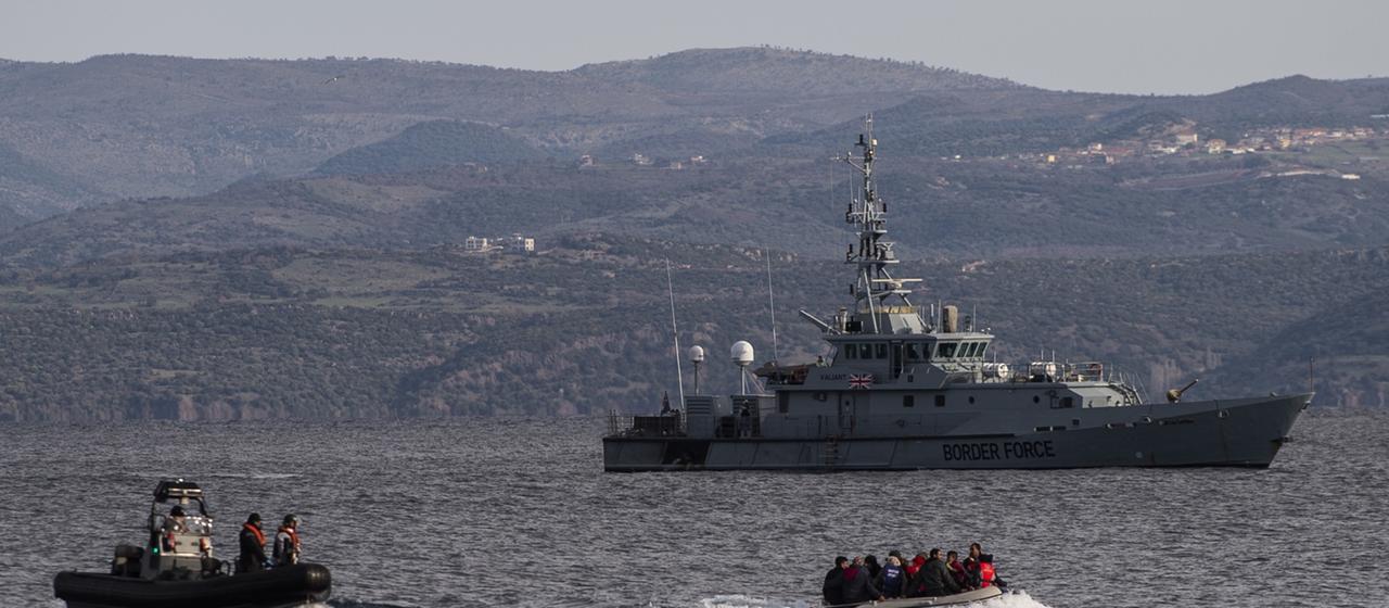Ein Boot mit Flüchtlingen fährt auf die griechische Insel Lesbos vor, begleitet von einem Patrouillenboot der britischen Grenztruppen HMC Valiant, das Teil der Frontex Mission ist.