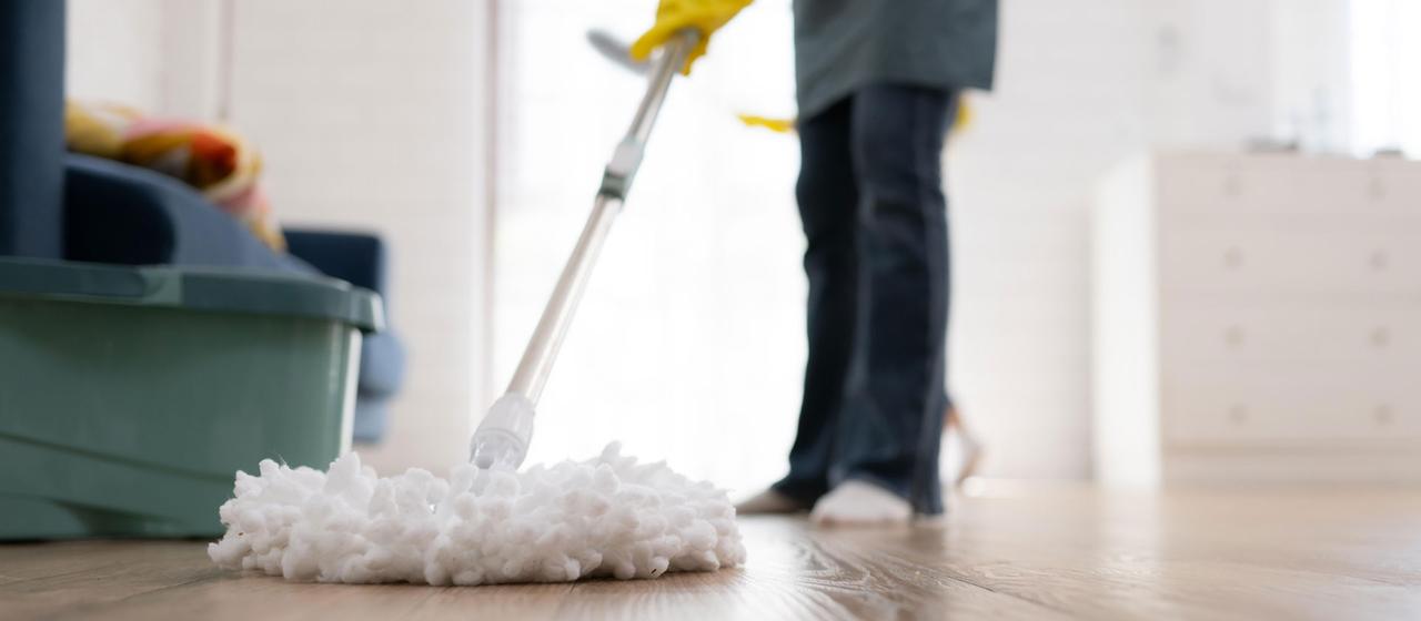 Eine Frau reinigt mit einem Wischmopp den Boden.