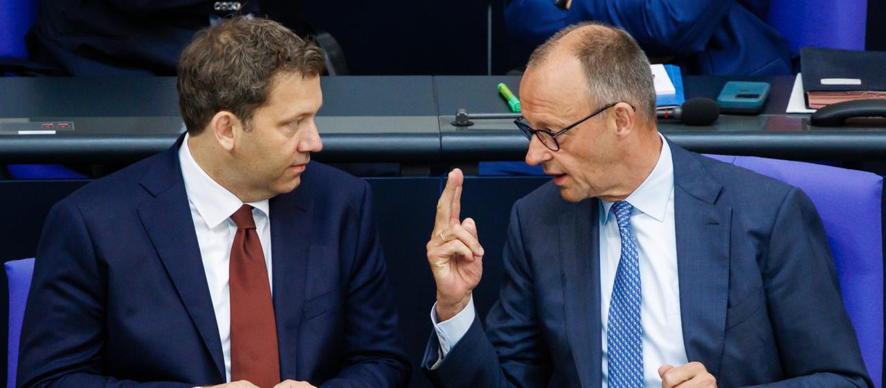 Lars Klingbeil und Friedrich Merz unterhalten sich im Bundestag.