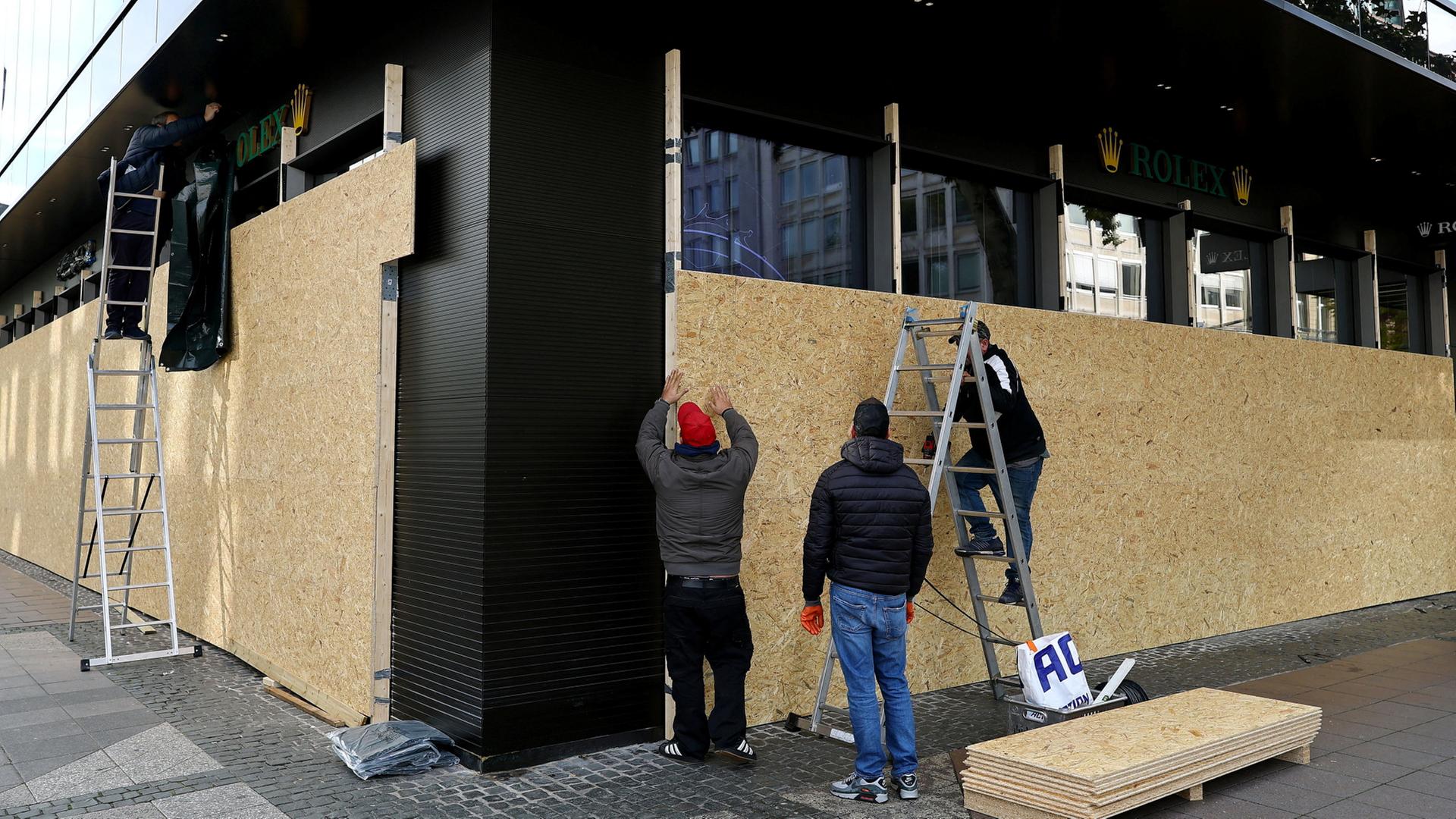 Mitarbeiter sichern ein Geschäft in Frankfurt am Main mit Holzbrettern ab. | REUTERS