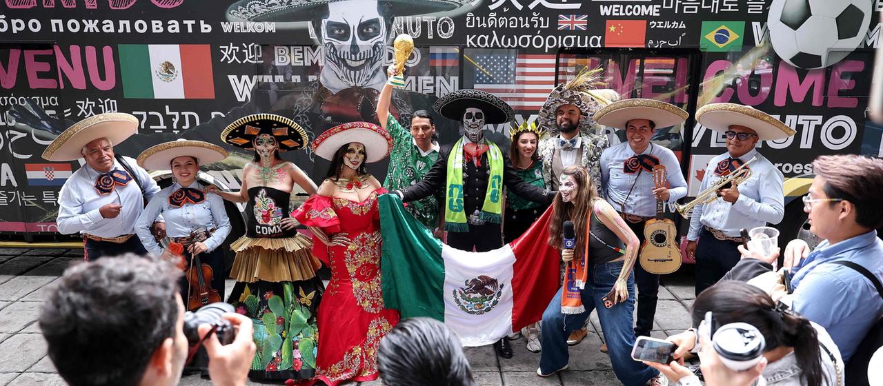 Kostümierte posieren mit Fußballfans in Mexiko