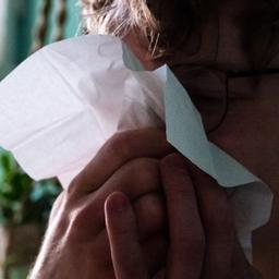 Ein Mann putzt sich die Nase.