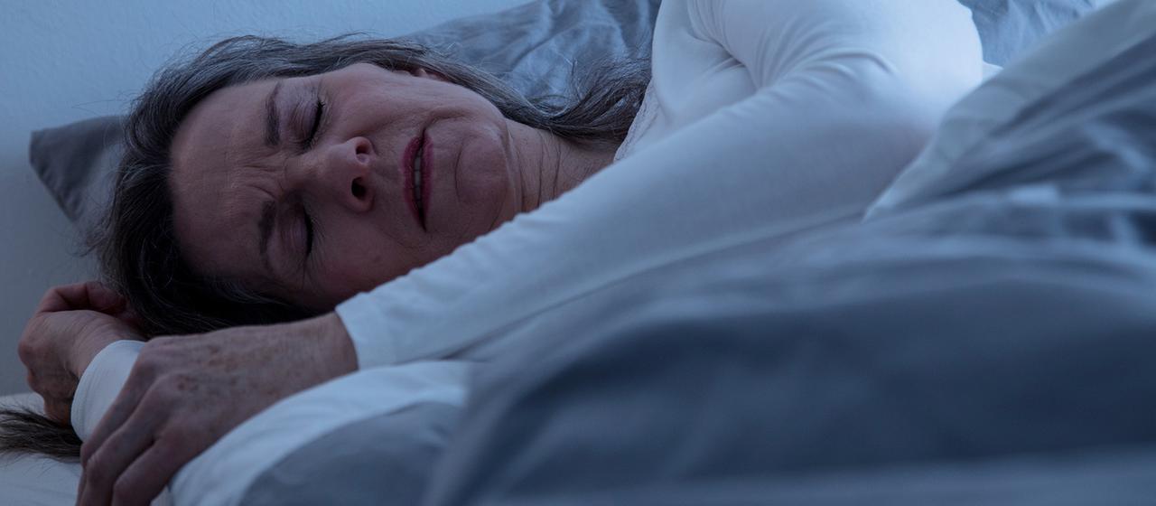 A woman lies in bed and sleeps.