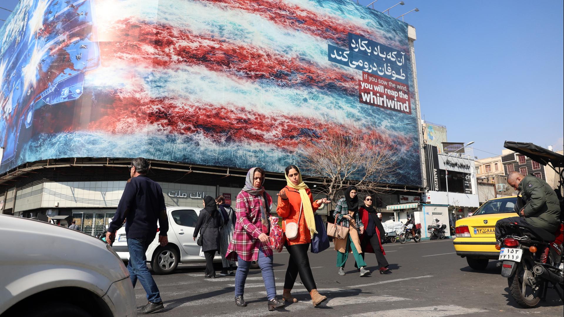 Passanten laufen in der iranischen Hauptadt Teheran an einer Plakatwand vorbei, die die US-Flagge zeigt. | EPA