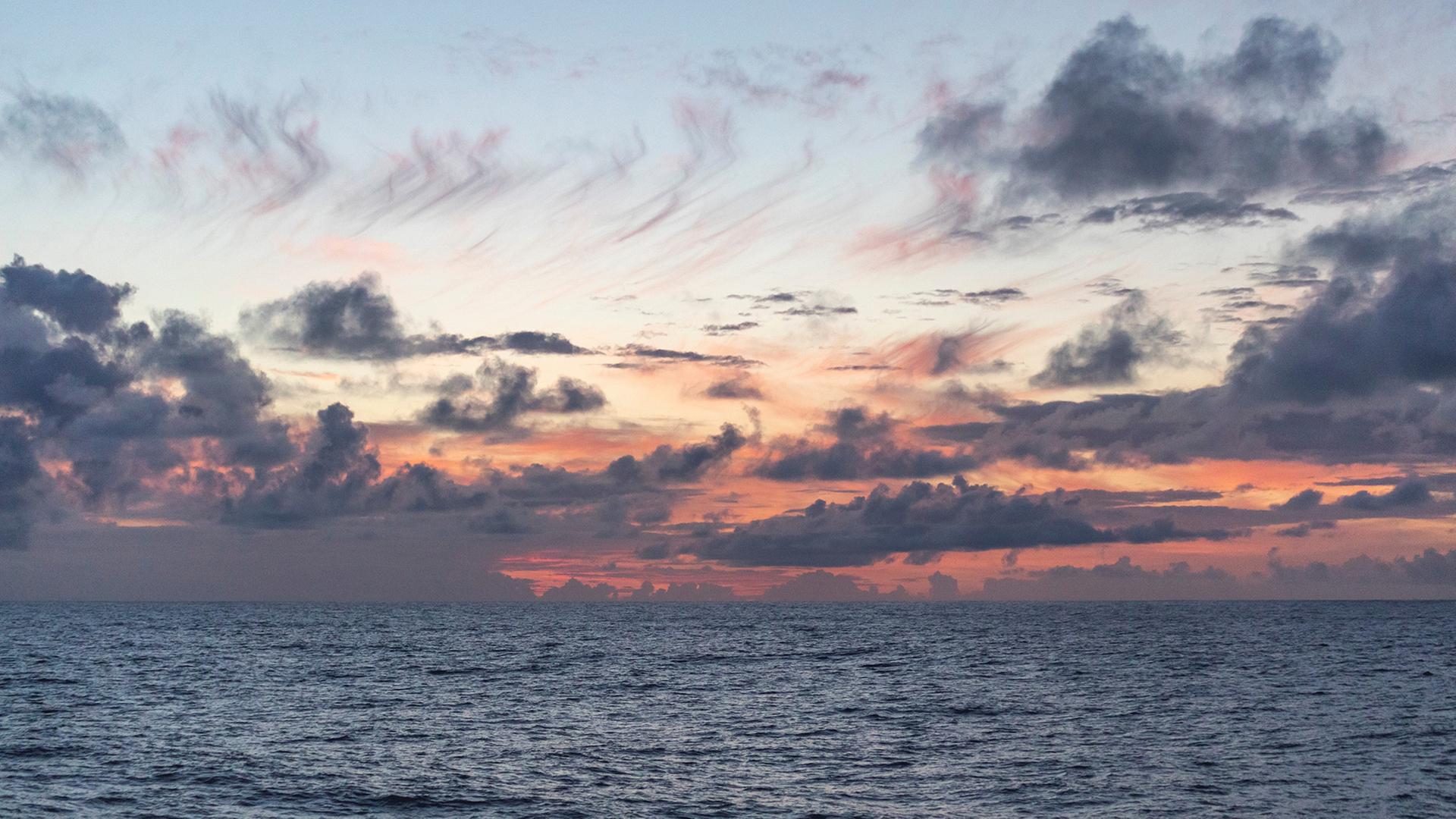Von der Sonne rötlich gefärbter Himmel am Horizont hinter dem Meer | Ryan Tabata/University of Hawaii at Manoa/dpa
