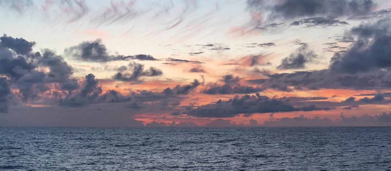 Sky colored red by the sun on the horizon behind the sea